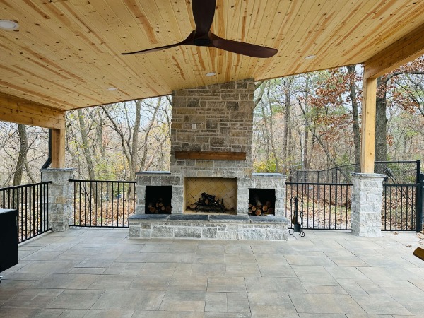 stone outdoor fireplace under a shade structure